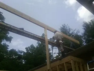Carpenter setting a ridge beam over a new addition frame — Ice Dam Removal by Roofing Brothers in Toney