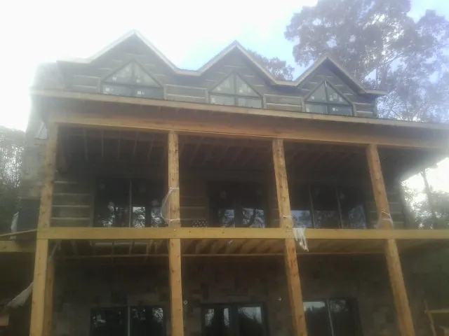 Dormers and porch framing on a large log home under construction — Roof Coating work by our crew in Toney