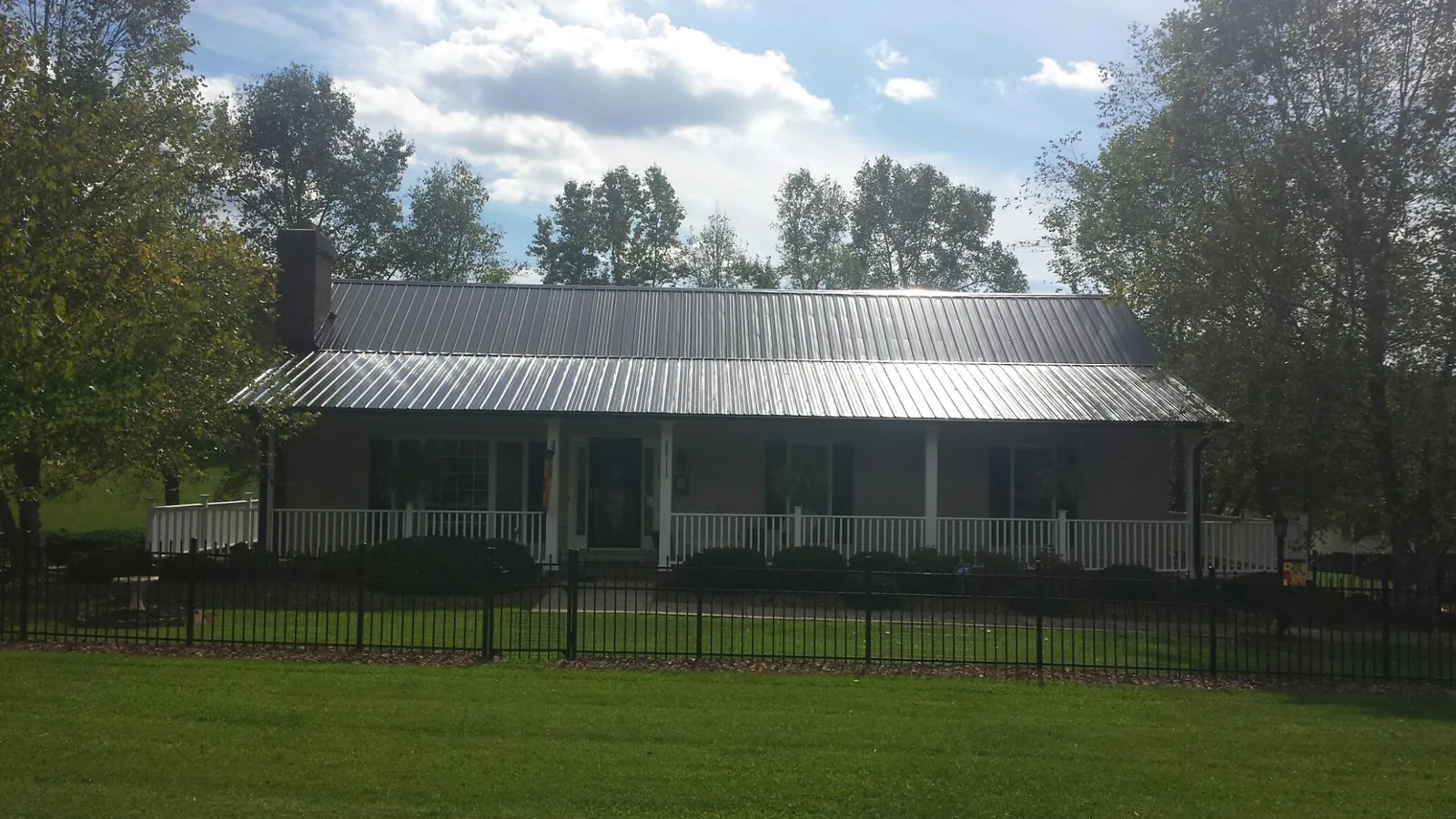 Gray metal roof on a brick ranch with a full width front porch — Gutter Guard Installation work by our crew in Toney